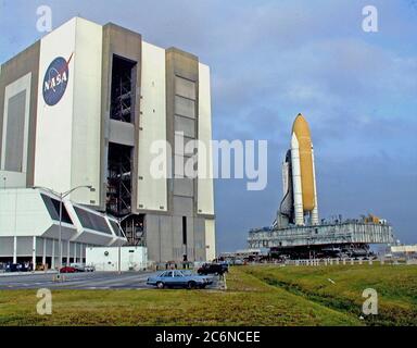 Der Space Shuttle Discovery ragt über die mobile Trägerrakete und den Crawler-Transporter und fährt aus dem Vehicle Assembly Building zum Launch Pad 39B, das 4.2 Meilen (6.8 Kilometer) entfernt ist. Während der Zeit auf dem Pad werden Orbiter, externer Tank und solide Raketenverstärker den letzten Vorbereitungen für den STS-103 Start unterzogen, der für den 6. Dezember 1999 um 2:37 Uhr EST geplant ist. Stockfoto