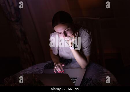 Freiberufliche Mitarbeiterin, die spät abends zu Hause am Laptop arbeitet und soziale Medien teilt. Distanzauftrag Stockfoto