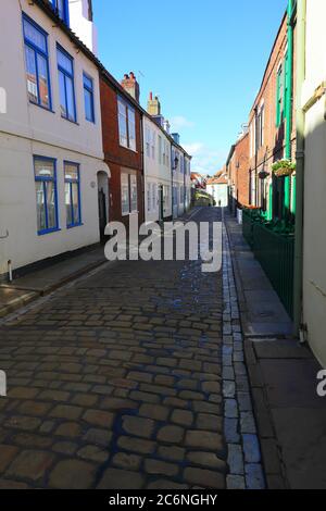 Cobblled Street mit blauem Himmel und Reihenhäusern in Whitby, North Yorkshire, England, Großbritannien Stockfoto