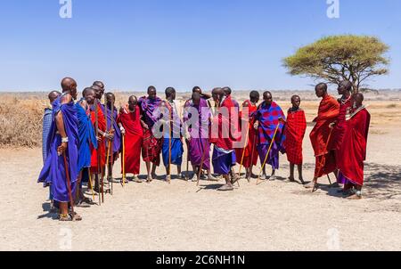 Serengeti, Tansania - September 21. 2012: Eine Gruppe von Massai-Männern in bunten Stoffen, die in einem Massai-Dorf im Serengeti National Pa zusammenkommen Stockfoto