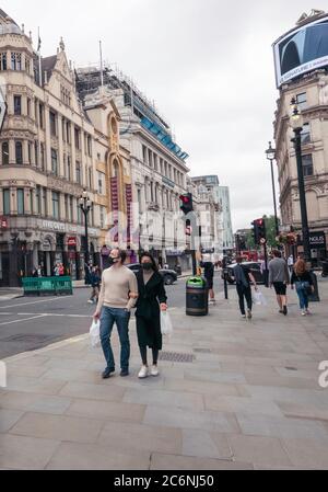 Ein Mann und eine Frau mit Gesichtsbedeckungen im Piccadilly Circus während der Pandemie covid-19. Stockfoto