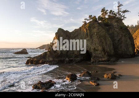 Ruhiger Strand an der südlichen Küste von Oregon, bekannt als Secret Beach mit wunderschönen Inseln, gekrönt von immergrünen Bäumen an einem schönen sonnigen Tag Stockfoto