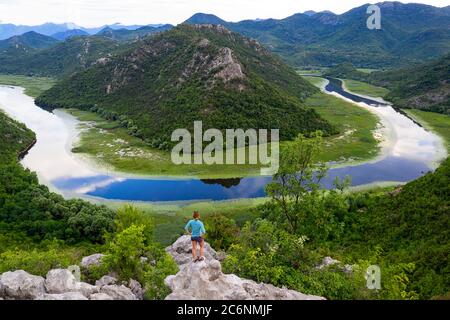 Frau auf einem Felsen über der Flussbiegung des Flusses Rijeka Crnojevica, Blick vom Aussichtspunkt Pavlova strana, in der Nähe von Cetinje Stockfoto