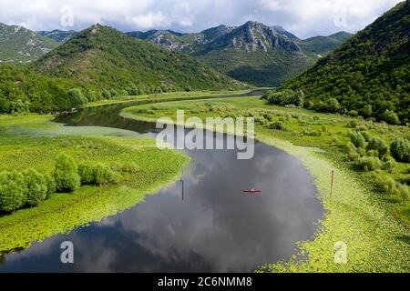 Frau im roten Kajak paddeln auf dem Fluss Rijeka Crnojevica, in der Nähe von Cetinje Stockfoto