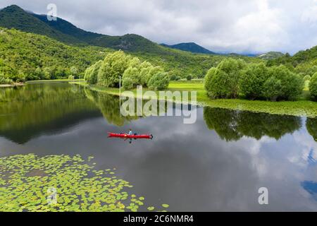 Frau im roten Kajak paddeln auf dem Fluss Rijeka Crnojevica, in der Nähe von Cetinje Stockfoto