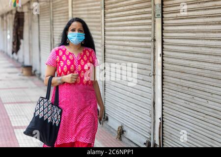 Indische Dame mit Corona-Maske vor geschlossenen Geschäften auf Janpath Straße in Connaught Place Stockfoto