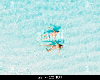 Schwangere Frau mit Mann entspannen am tropischen Strand mit Meer. Luftaufnahme Stockfoto