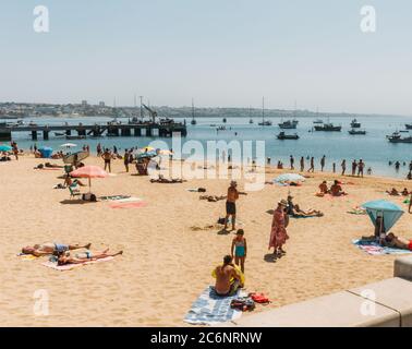 Cascais, Portugal - 11. Juli 2020: Strand Praia da Ribeira in Cascais, Portugal. Frau trägt Gesichtsmaske am Strand wegen Coronavirus Covid-19 Ausbruch Stockfoto