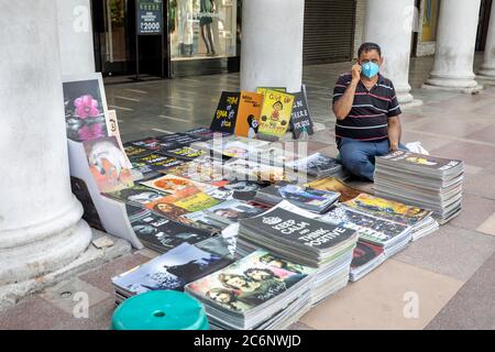 Ein Straßenverkäufer trägt Corona-Schutzmaske sitzt in Connaught Place Stockfoto