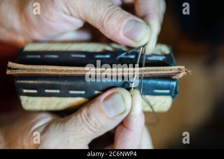 Herrenhände sind mit einer Handnaht groß aus Leder genäht. Stockfoto