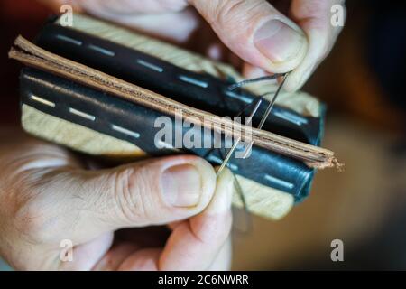 Herrenhände sind mit einer Handnaht groß aus Leder genäht. Stockfoto