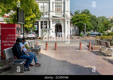Zwei indische Männer mit Corona-Schutzmasken sitzen auf einer Bank im Connaught Place, Stockfoto