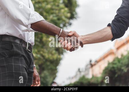 Handschlag zwischen afrikaner und einem kaukasischen Mann im Freien Stockfoto