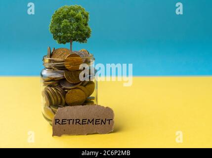 Geldmünzen und Baum wachsen im Glas. Gewinn auf Einlage in Bank und Dividende für Aktienanlagekonzept. Text für den Ruhestand im Vordergrund Stockfoto