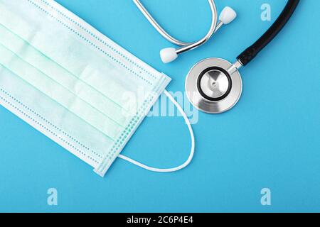 Stethoskop und OP-Maske auf blauem Hintergrund, flach liegend Stockfoto
