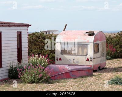 Ein altes Wohnmobil und Boot im Weiler Dungeness, einer Landzunge an der Küste von Kent, England, bildete weitgehend aus einem Kiesstrand. Stockfoto