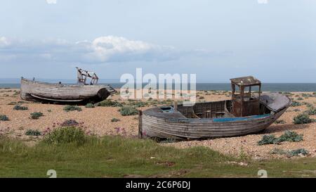 Zwei verlassene Fischerboote am Dungeness Beach, einer Landzunge an der Küste von Kent, England, bildeten größtenteils einen Kiesstrand. Stockfoto