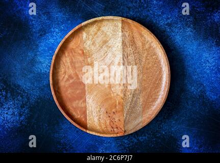 Draufsicht auf hölzerne runde Platte für Pizza auf Kontrast Dunkelblauer Hintergrund Stockfoto