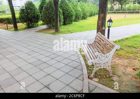 Blick auf grünen Garten mit einem kleinen Platz und Holzbank für Resing in der Ecke des Stadtparks, Fuzhou, Fujian, China Stockfoto