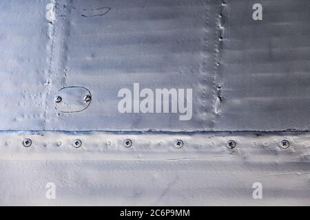 Flugzeughaut Nahaufnahme. Nieten auf grauem Metall. Hintergrund für Design. Stockfoto