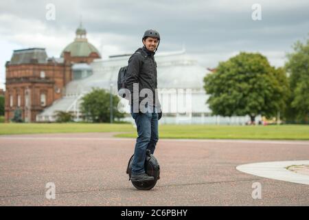 Glasgow, Schottland, Großbritannien. Juli 2020. Bild: Ein Einheimischer ist gesehen Reiten sein Elektro-Einrad trägt eine blaue OP-Maske unter Übung in Glasgow Green während der Lockdown. Da Elektroroller sind jetzt die Norm, sind elektrische Einräder gehen, um auf zu fangen? Quelle: Colin Fisher/Alamy Live News Stockfoto