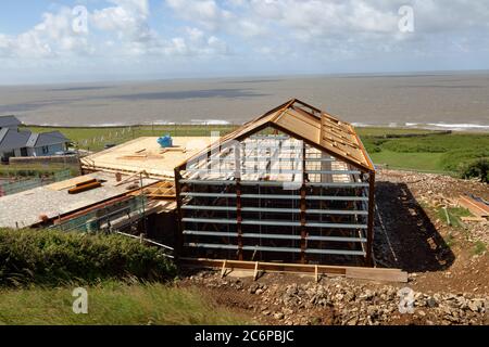 Das lang erwartete Dorfhaus im Bau in Ogmore am Meer mit seiner Stahlrahmenschale und neue hölzerne künstlerische Dachkonstruktion im Rahmen. Stockfoto