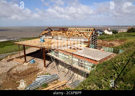 Das lang erwartete Dorfhaus im Bau in Ogmore am Meer mit seiner Stahlrahmenschale und neue hölzerne künstlerische Dachkonstruktion im Rahmen. Stockfoto