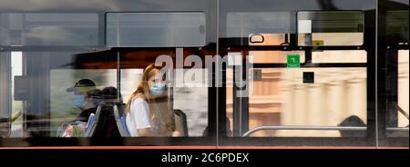 Belgrad, Serbien - 4. Juli 2020: Eine Jugendliche Frau mit Gesichtsmaske, die auf dem Fensterplatz eines öffentlichen Nahverkehrs-Busses reitet Stockfoto