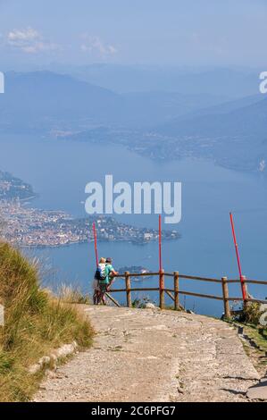 Zwei Touristen, die innehalten, um den Blick auf den Lago Maggiore von Mottarone, Italien, zu bewundern Stockfoto