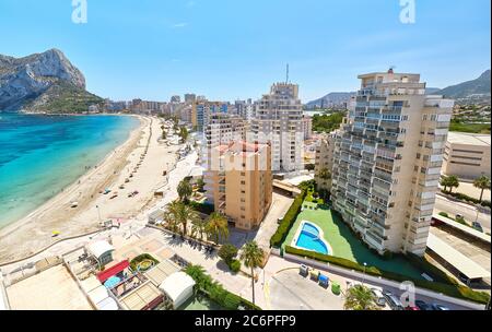 Sandstrand mit Sonnenschirmen und Urlaubern, Blick auf den Penyal d'IFAC Naturpark. Türkisblaues Meerwasser Sommertag. Strandpromenade von Calpe spanish r Stockfoto