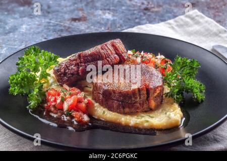 Rindermedaillons mit Tomatensalsa und Rahm Polenta Stockfoto