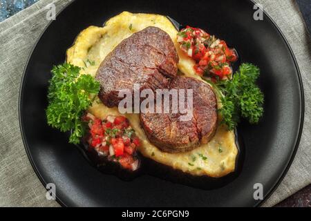 Rindermedaillons mit Tomatensalsa und Rahm Polenta Stockfoto