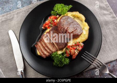 Rindermedaillons mit Tomatensalsa und Rahm Polenta Stockfoto