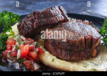 Rindermedaillons mit Tomatensalsa und Rahm Polenta Stockfoto