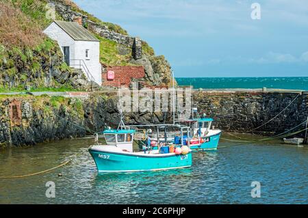 Porthgain Hafen an einem sonnigen Tag im Mai mit zwei Fischerbooten, die bei Flut festgemacht wurden. Pembrokeshire Coast National Park. Stockfoto