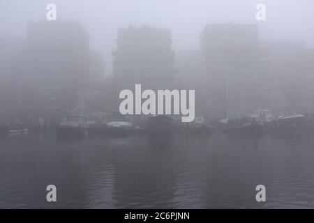 Ein nebliger Morgen in Amsterdam mit Gebäuden am Ufer des Westerdok Stockfoto