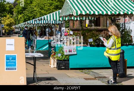 Ein Steward mit Gesichtsmaske auf Farmers Market während der Covid-19 Pandemie, Haddington, East Lothian, Schottland, Großbritannien Stockfoto