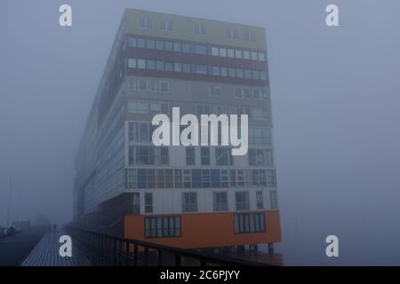 Ein nebliger Morgen in Amsterdam mit Gebäuden am Wasser Stockfoto