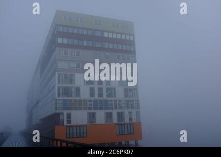 Ein nebliger Morgen in Amsterdam mit Gebäuden am Wasser Stockfoto