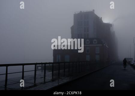 Ein nebliger Morgen in Amsterdam mit Gebäuden am Wasser Stockfoto