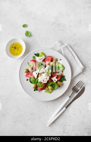 Griechischer Salat mit Cucumeber, Oliven, Feta, Tomaten und frischem Basilikum. Hausgemachter frischer mediterraner Salat mit Ziegenkäse, gesunde vegetarische mea Stockfoto