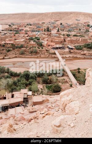 Aussichtspunkt Desert Village, aufgenommen von der Spitze des Ait Benhaddou in Marokko, zeigt rote Sandsteingebäude über einem trockenen Flussbett. Stockfoto