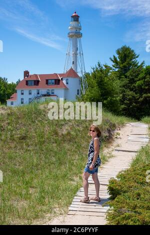 Rawley Point Leuchtturm in Two Rivers, Wisconsin mit einer Dame, die im Sommer auf dem Holzweg geht, vertikal Stockfoto