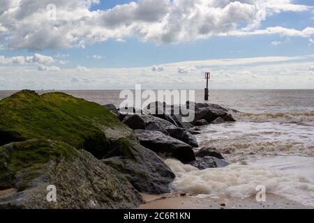 Wellen krachen über Felsen, Meeresverteidigung an der Suffolk Küste Stockfoto