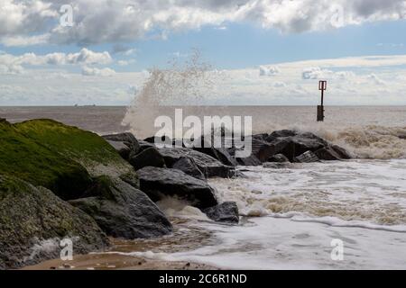 Wellen krachen über Felsen, Meeresverteidigung an der Suffolk Küste Stockfoto