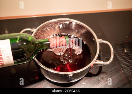 Glühwein wird in einen Topf gegossen, um ihn aufzuwärmen Stockfoto