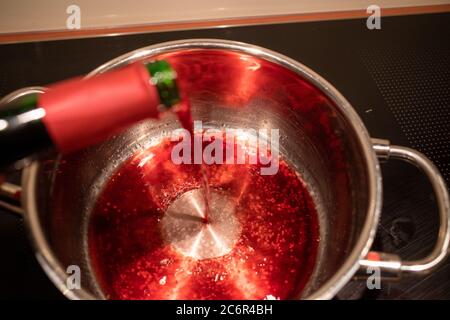 Glühwein wird in einen Topf gegossen, um ihn aufzuwärmen Stockfoto