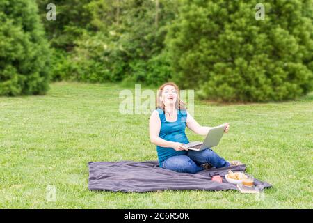 Schöne schwangere Frau lacht in einem Sommer grünen Park mit Laptop und Fahrrad. Stockfoto