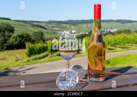 Weinflasche mit Gläsern auf Holztisch mit Landschaft an der mosel im Hintergrund Stockfoto