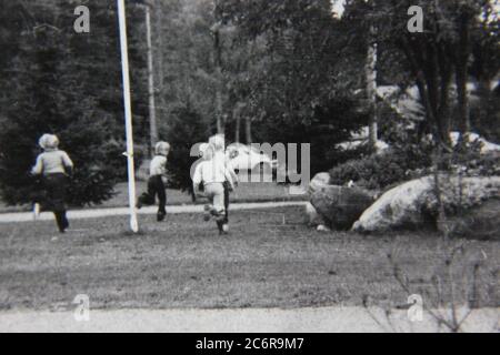 Feine 70er Jahre Vintage schwarz-weiß Lifestyle-Fotografie von Kindern im Park spielen. Stockfoto